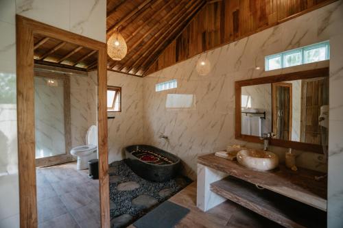 a bathroom with a tub and a sink and a mirror at Umah Bali Kuno Villa New in Tampaksiring