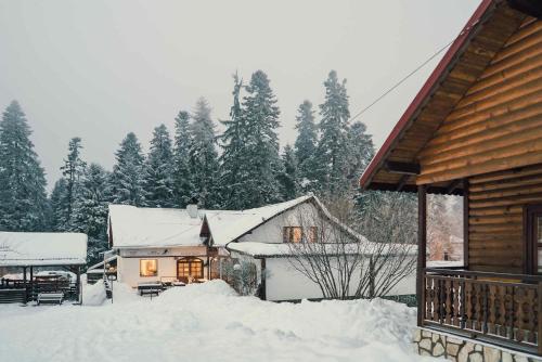 a house covered in snow next to a cabin at Complex Popangelov in Borovets
