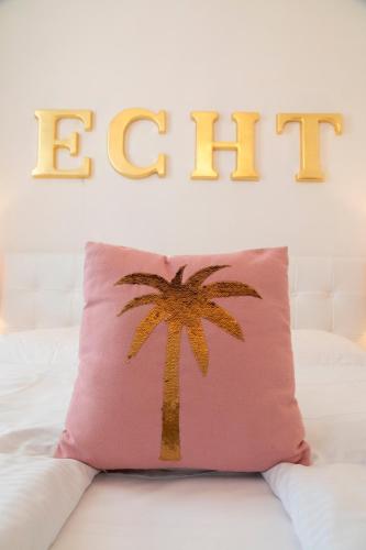 a palm tree pillow sitting on a bed with the word eat at Hotel Schwalbe in Vienna