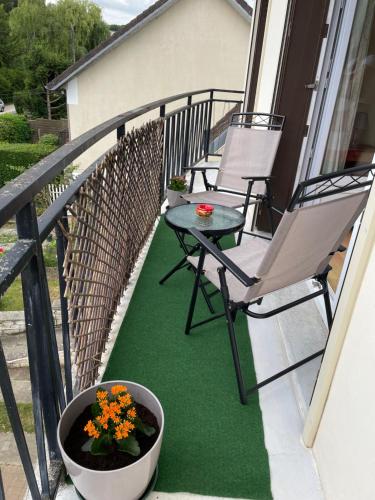 - un balcon avec 2 chaises, une table et des fleurs dans l'établissement Appartement 3 pièces, à Mareil-Marly