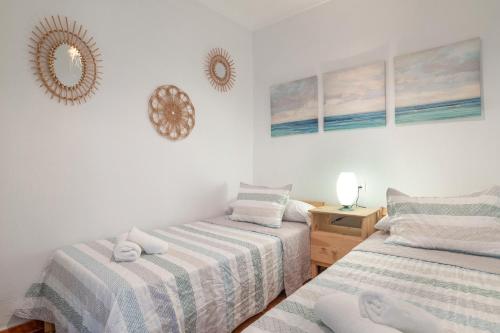 a bedroom with two beds and a mirror on the wall at Apartamento Centro Conil - Andalmar in Conil de la Frontera