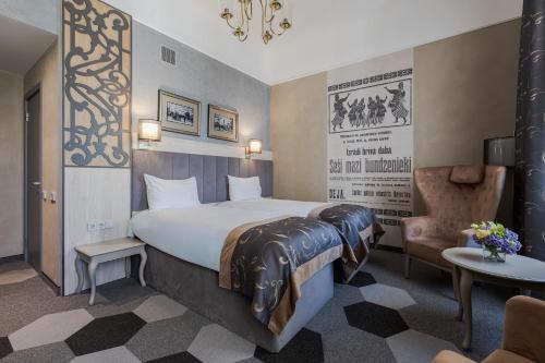 a hotel room with a large bed and a chair at Eurostars Metropole in Rīga