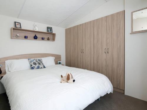 a bedroom with a white bed with a dog laying on it at Nature's Nook - Billing Aquadrome in Northampton