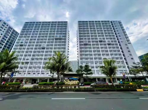 two tall buildings with palm trees in front of a street at SLY Staycation at Shore Residences Mall of Asia in Manila