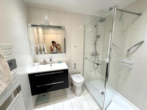 une femme prenant une photo d'une salle de bain avec toilettes et douche dans l'établissement ApartHotel Riviera - Terrasse Loft de la Providence - Vieille Ville - Esprit Loft en 2 pices AC, à Nice