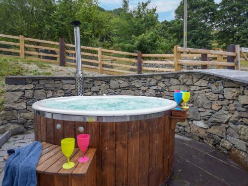 a hot tub with two drinking glasses on a wooden deck at 3 bed in Corwen 86266 in Corwen