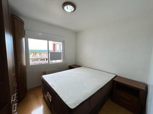 a small bedroom with a bed and a window at Gramado Village Apartamento no Centro in Gramado