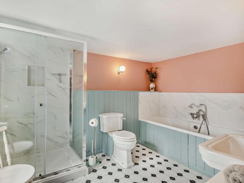 a bathroom with a toilet and a tub and a sink at 3 Bed in Mundesley 90398 in Mundesley