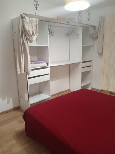 une chambre avec des étagères blanches et un lit rouge dans l'établissement Maison au pays des lavandes et de la vigne, à Pierrevert