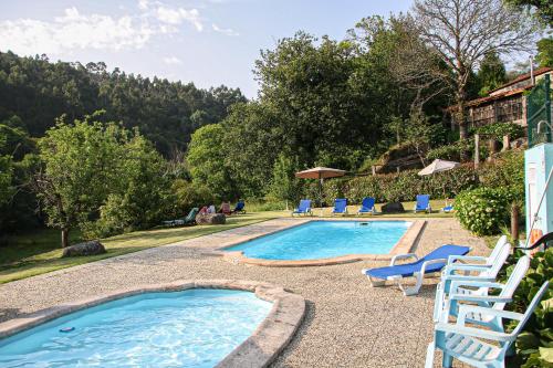Una piscina con tumbonas y un resort. en Quinta da Chanca, en Paredes de Coura