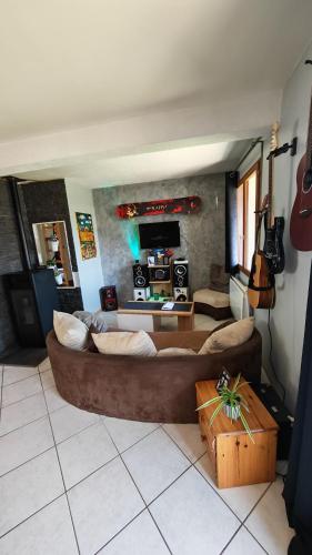 un salon avec un grand canapé marron et des instruments dans l'établissement Maison de vacances Valuejols, à Valuéjols
