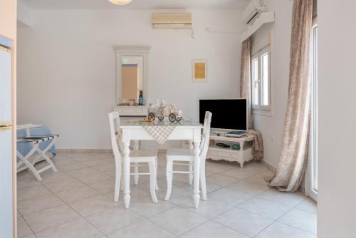 a white dining room with a white table and chairs at Caldera Studios in Astypalaia Town
