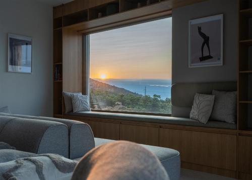a man looking out a window at the sunset at Villa Ladeti Sereno in Poljane