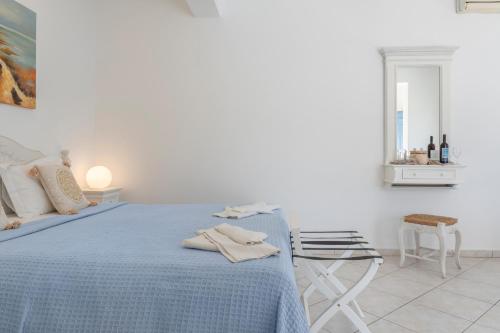 a white bedroom with a blue bed and a stool at Caldera Studios in Astypalaia Town