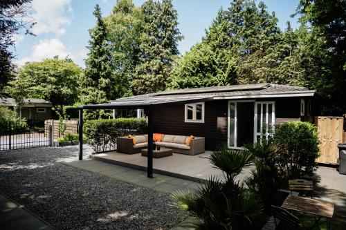 a tiny house with a porch and a couch at Veluwse Wellness Lodge Selina in Ermelo