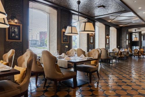 a restaurant with tables and chairs and a large window at Eurostars Metropole in Rīga