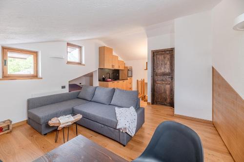 a living room with a gray couch and a kitchen at Nest-home in front to Mont Blanc in Courmayeur