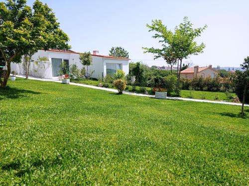 a yard with green grass and a white house at LAR JARDÍN - Casas con parking privado in Santiago de Compostela