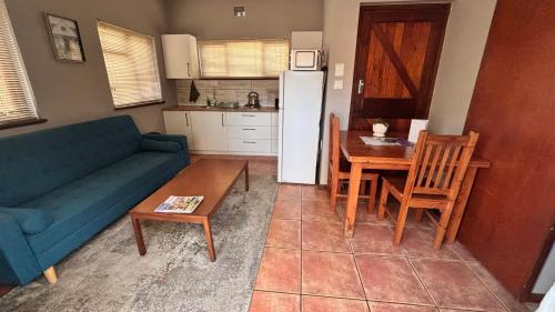 a living room with a couch and a table and a kitchen at Eike Cottage in George