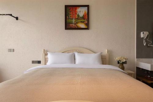a bedroom with a white bed with a picture on the wall at Dali Blue House Sea View B&B in Dali Ancient Town