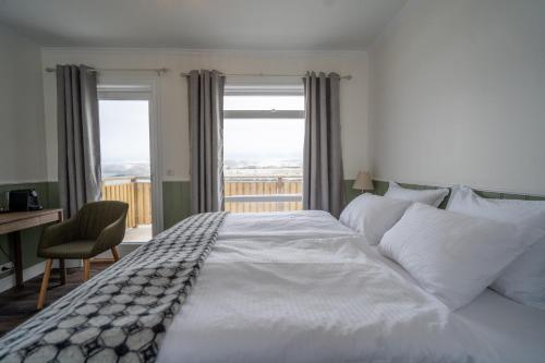 a large white bed in a bedroom with a window at Hótel Blönduós in Blönduós