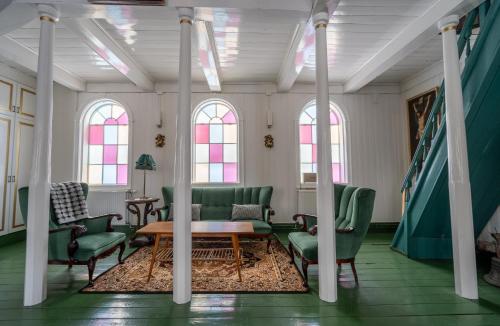 a room with green chairs and a table and windows at Hótel Blönduós in Blönduós