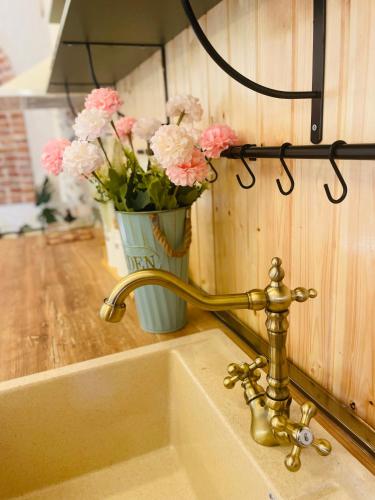 a sink with a faucet and a vase of flowers at House of Warmth in Bagdatʼi