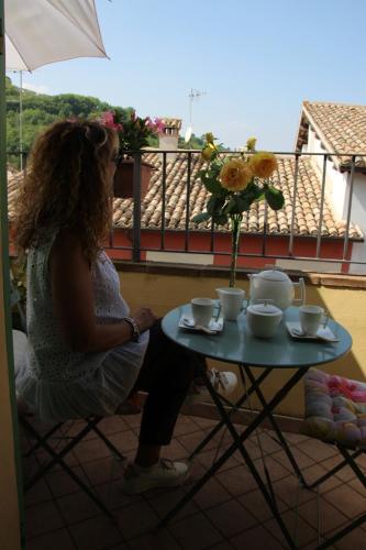 a woman sitting at a table with a vase of flowers at La Casa del Borgo Antico in Spoleto