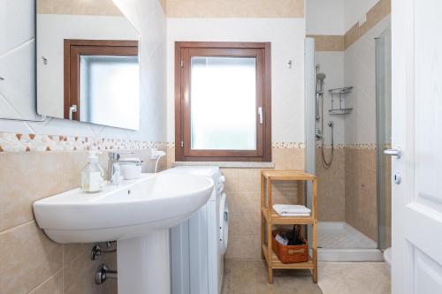 a white bathroom with a sink and a shower at Villa Bouganville Cala Sinzias in Castiadas