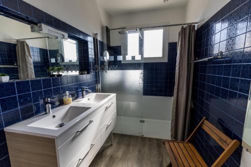 baño con lavabo y ducha con azulejos azules en Gite west landes, en Onesse-et-Laharie