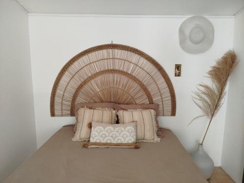 a bed with a large wicker headboard in a room at Petit cocon vue mer in Gourbeyre