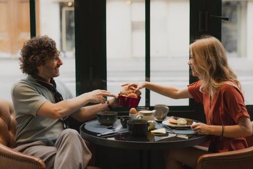 un uomo e una donna seduti a un tavolo che mangiano cibo di Hôtel Belleval a Parigi