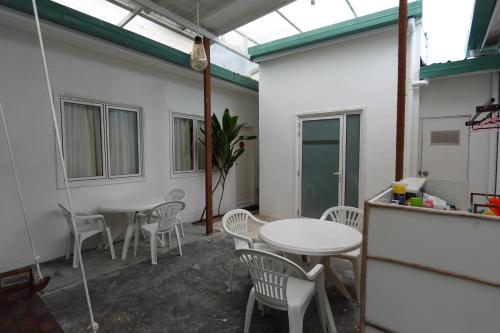 a room with two tables and chairs and windows at Stay Kora in Thinadhoo