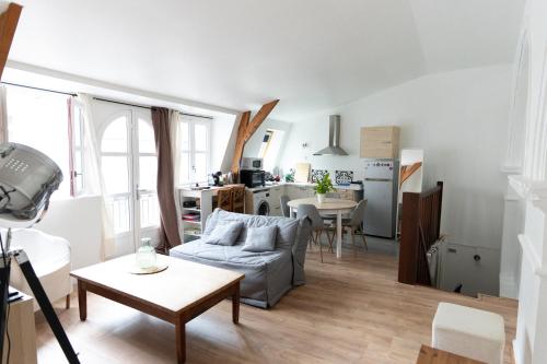 un salon avec un canapé et une cuisine dans l'établissement L'écrin de Fontenelle, à Rouen