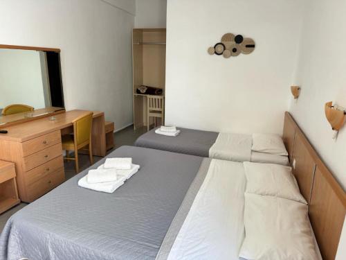 a bedroom with two beds and a desk and a mirror at Villa Markos in Perissa