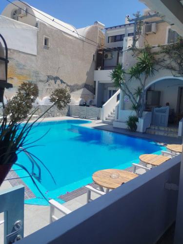 a large blue swimming pool with a table and chairs at Villa Markos in Perissa