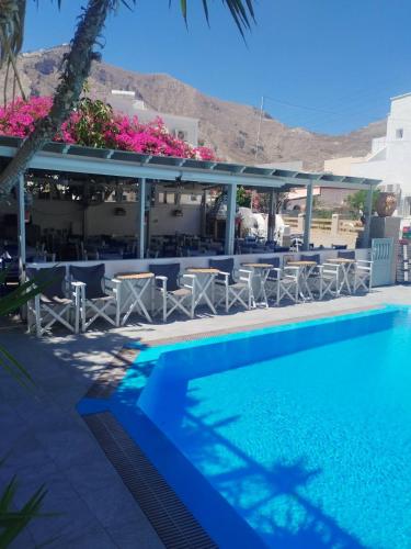 a pool at a hotel with tables and chairs at Villa Markos in Perissa