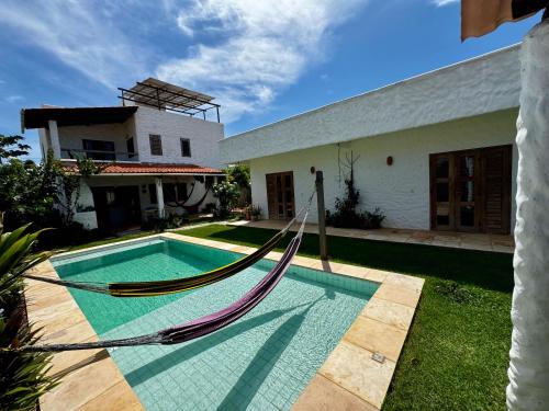 a pool with a hammock in front of a house at Casa Kuara in Trairi