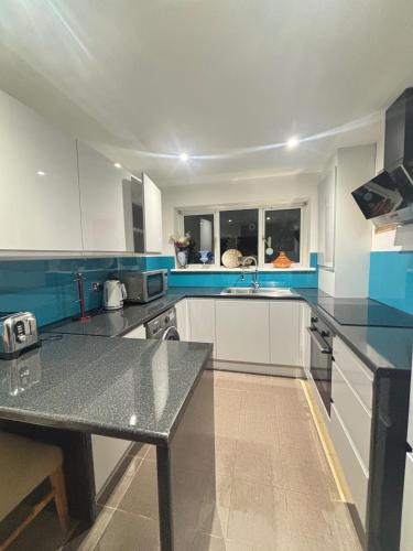 a large kitchen with white cabinets and blue accents at 2 Bed-Sleeps 5-Private Garden-Free Parking in High Wycombe