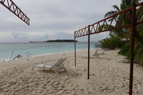two chairs on a beach with the ocean at Stay Kora in Thinadhoo