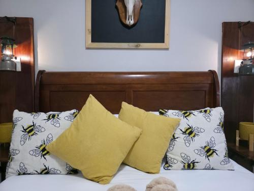 a bed with yellow and white pillows and a headboard at Ukulala Inn in Malelane