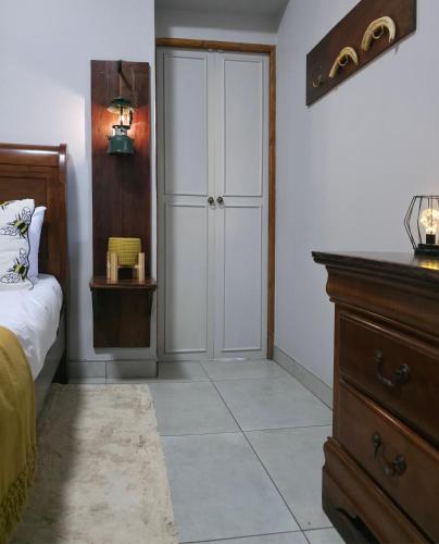a bedroom with a bed and a dresser and a closet at Ukulala Inn in Malelane