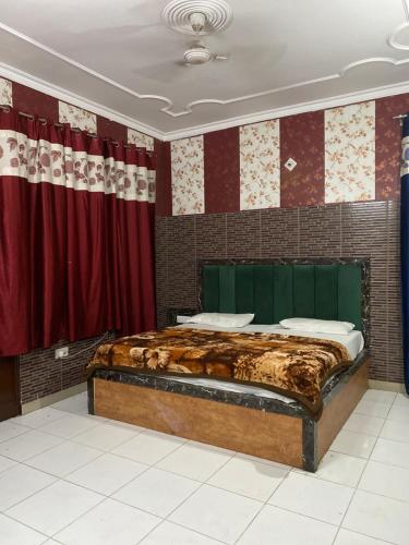 Cama grande en habitación con cortinas rojas en Hotel Tara Palace By MIDTOWN, en Katra