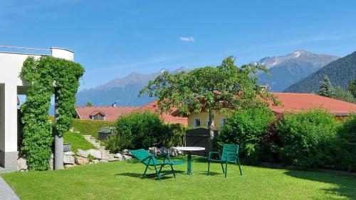 a patio with chairs and a table in the grass at Haus Monika in Obsteig