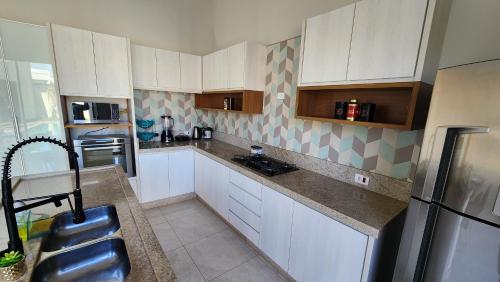 a kitchen with white cabinets and a stainless steel refrigerator at Casa Espetacular, 3 suites, luxo! in Maringá