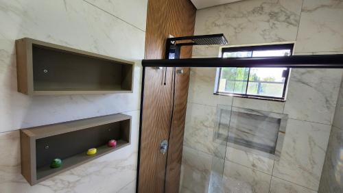 a bathroom with a shower with a glass door at Casa Espetacular, 3 suites, luxo! in Maringá
