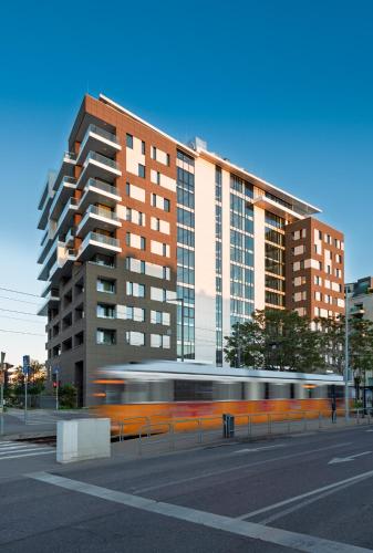 a bus driving in front of a tall building at INFINITY Budapest Hotel in Budapest