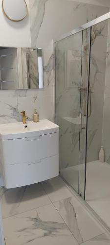 a white bathroom with a sink and a shower at Noclegi Gwardia in Koszalin