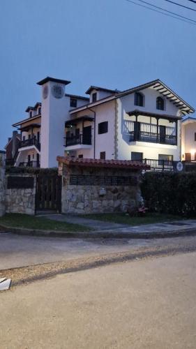 a large white house with a stone fence in front of it at Apartamentos Turísticos El Puerto de Comillas in Comillas