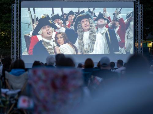 a crowd of people watching a movie on a screen at Harbour Stays at Ocean Square in Saundersfoot